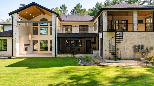 back of property with ceiling fan, a balcony, a yard, and a patio