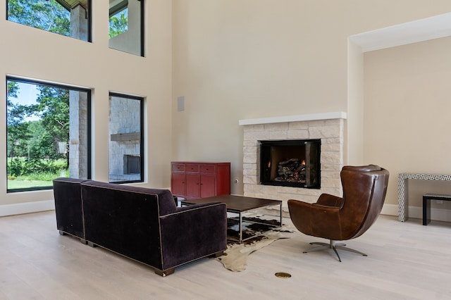 living room featuring wood-type flooring, a fireplace, and a towering ceiling