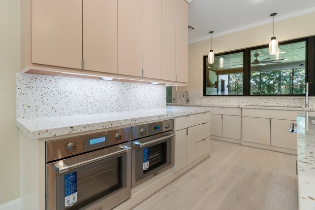 kitchen with ornamental molding, pendant lighting, light stone countertops, and stainless steel oven