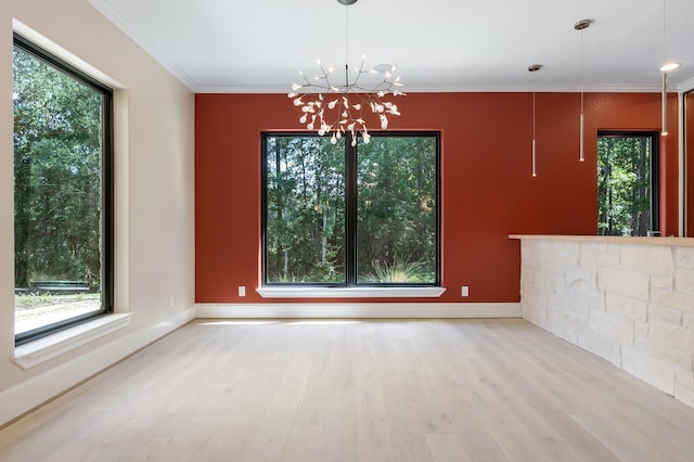 unfurnished dining area with ornamental molding, a notable chandelier, and light hardwood / wood-style floors