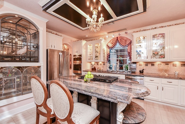 kitchen featuring light stone countertops, backsplash, appliances with stainless steel finishes, and white cabinetry