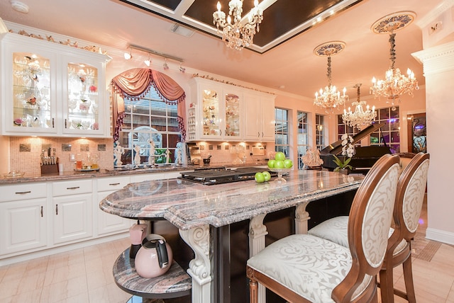 kitchen featuring decorative backsplash, light stone countertops, white cabinets, and a breakfast bar area