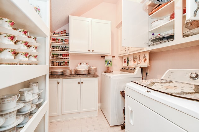 laundry area featuring light tile patterned flooring, independent washer and dryer, and cabinets