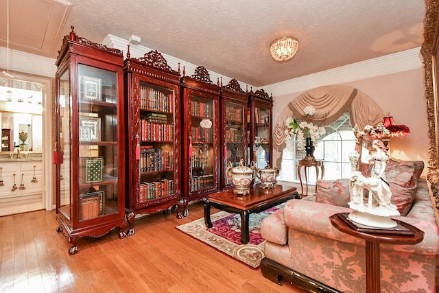 sitting room with hardwood / wood-style flooring, crown molding, and a textured ceiling