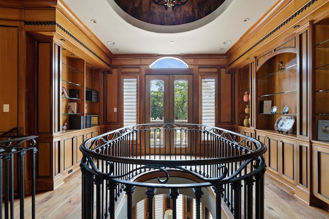 dining room featuring built in features, wooden walls, a raised ceiling, and light hardwood / wood-style floors