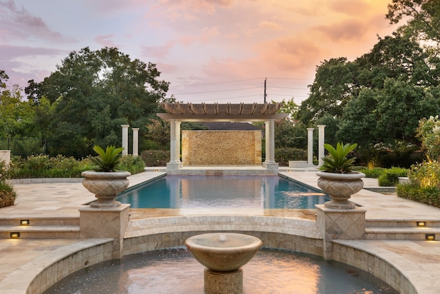 pool at dusk featuring a patio area