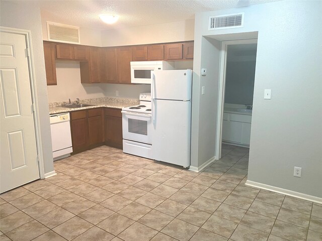 kitchen featuring a textured ceiling, sink, white appliances, and light tile patterned flooring