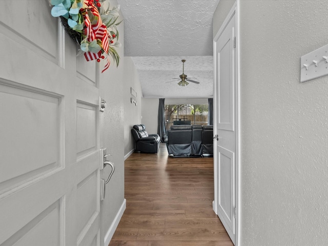 hallway featuring hardwood / wood-style floors, lofted ceiling, and a textured ceiling