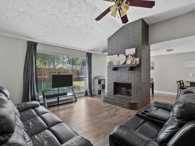 living room with a textured ceiling, ceiling fan, lofted ceiling, and a fireplace