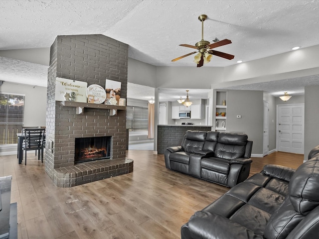 living room featuring a fireplace, a textured ceiling, vaulted ceiling, and ceiling fan