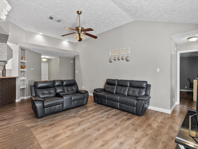 living room featuring lofted ceiling, built in features, hardwood / wood-style floors, and a textured ceiling