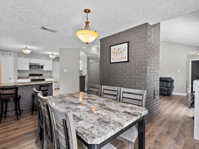 dining space featuring a textured ceiling and dark hardwood / wood-style floors