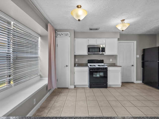 kitchen with white cabinetry, light tile patterned floors, black appliances, and a textured ceiling