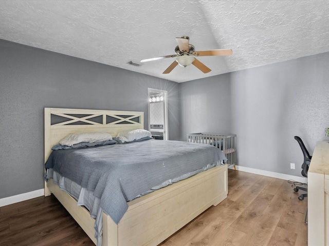 bedroom with wood-type flooring, a textured ceiling, and ceiling fan