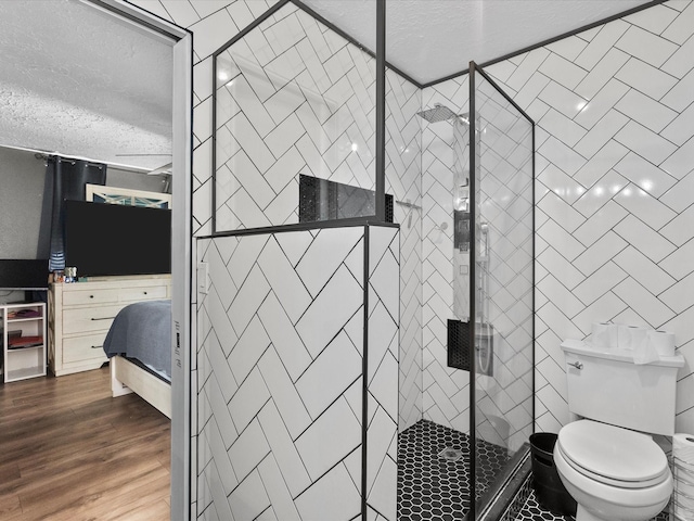 bathroom with hardwood / wood-style flooring, toilet, walk in shower, and a textured ceiling