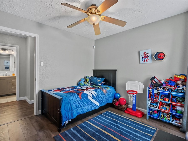 bedroom with a textured ceiling, dark hardwood / wood-style floors, ensuite bath, and ceiling fan