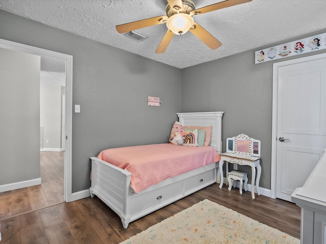 bedroom with ceiling fan, dark hardwood / wood-style flooring, and a textured ceiling