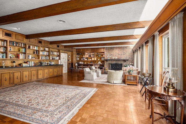 living room featuring built in shelves, beamed ceiling, a textured ceiling, and a fireplace