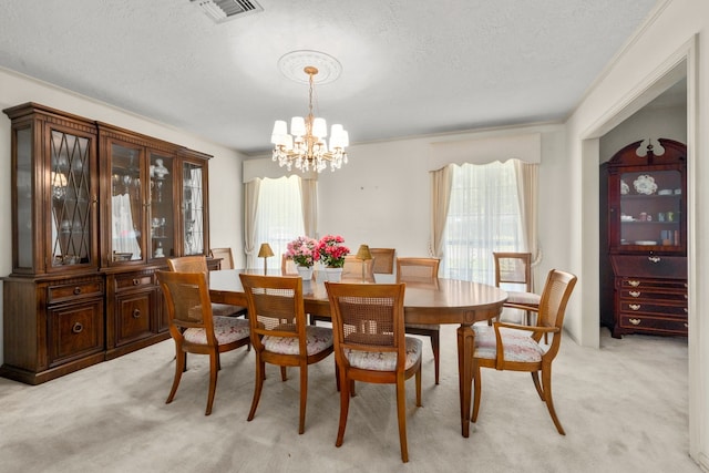 dining room featuring ornamental molding, light carpet, a notable chandelier, and a textured ceiling