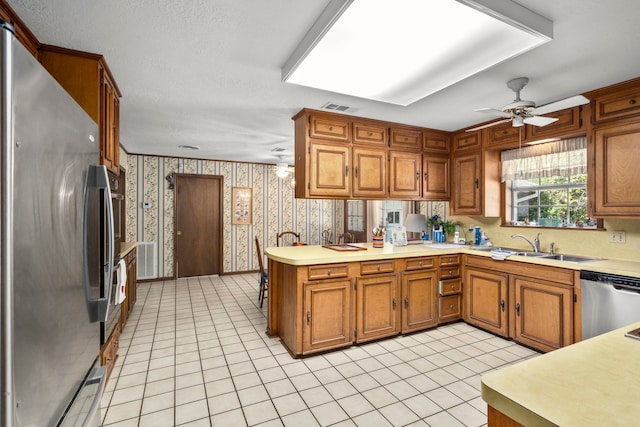 kitchen with ceiling fan, light tile patterned floors, sink, kitchen peninsula, and appliances with stainless steel finishes