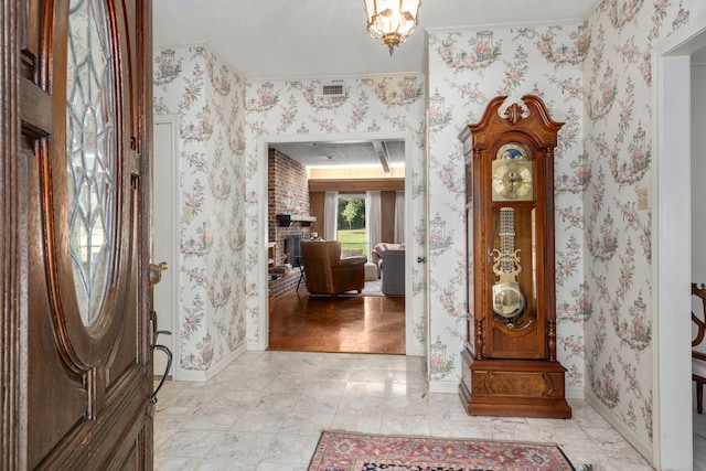 foyer entrance featuring a fireplace, light hardwood / wood-style flooring, and an inviting chandelier