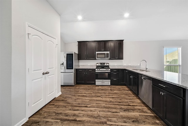 kitchen featuring light stone countertops, sink, dark wood-type flooring, kitchen peninsula, and appliances with stainless steel finishes