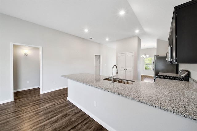 kitchen with kitchen peninsula, light stone counters, sink, an inviting chandelier, and range