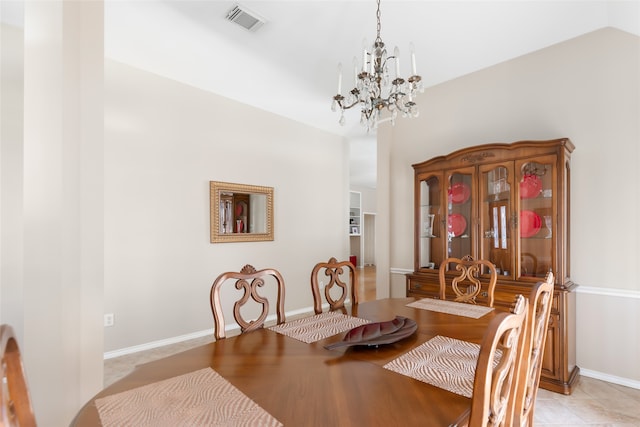 dining area featuring a notable chandelier, lofted ceiling, and light tile patterned flooring