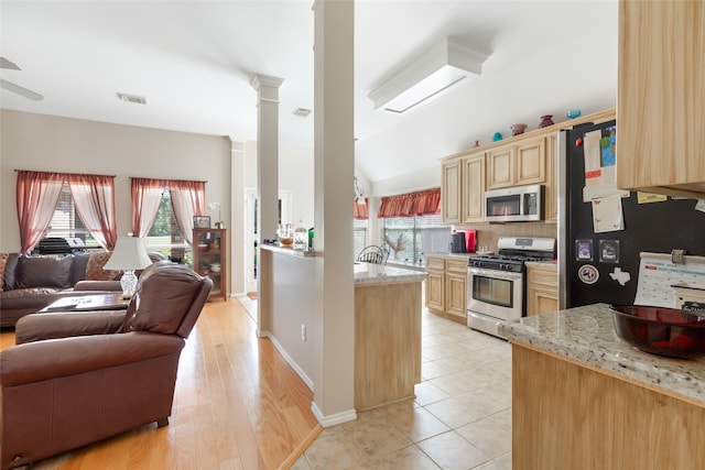 kitchen with light stone counters, light brown cabinets, ceiling fan, light hardwood / wood-style flooring, and stainless steel appliances