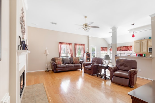 living room featuring ceiling fan, lofted ceiling, decorative columns, and light hardwood / wood-style floors