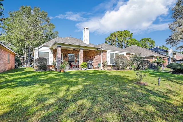 back of property with ceiling fan, a yard, and a patio area