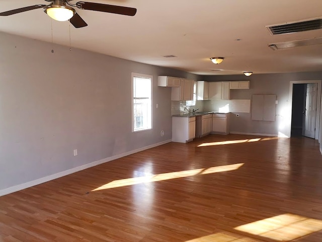 unfurnished living room featuring ceiling fan, sink, and hardwood / wood-style floors