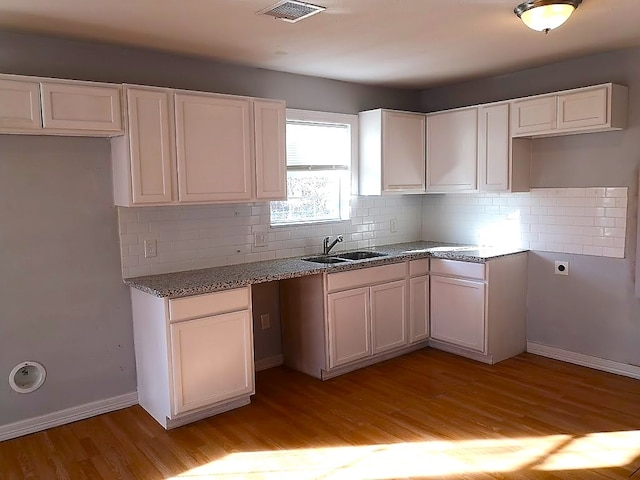 kitchen featuring light hardwood / wood-style flooring, backsplash, sink, and white cabinets