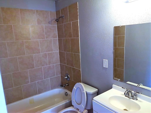 full bathroom with tiled shower / bath, vanity, and toilet