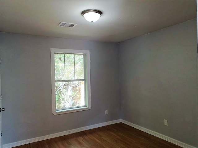 unfurnished room with baseboards, dark wood finished floors, and visible vents