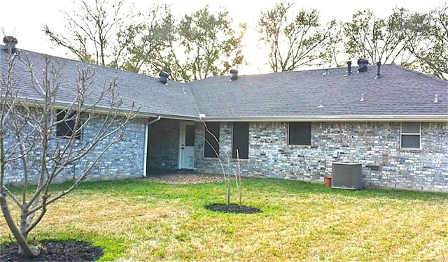 back of property with central AC unit and a lawn