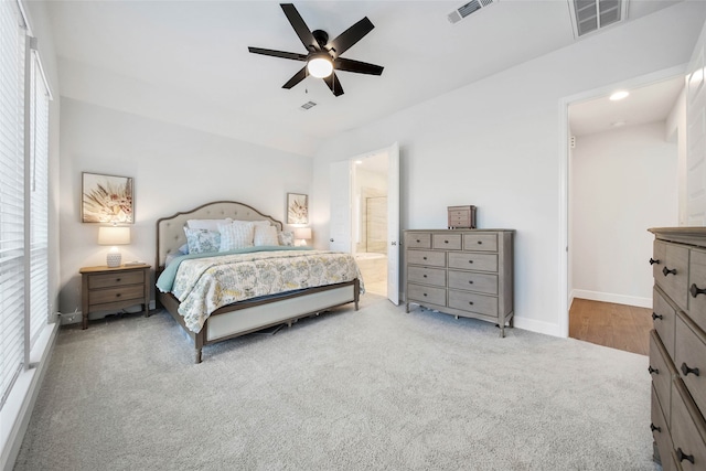 bedroom with light carpet, ensuite bath, and ceiling fan