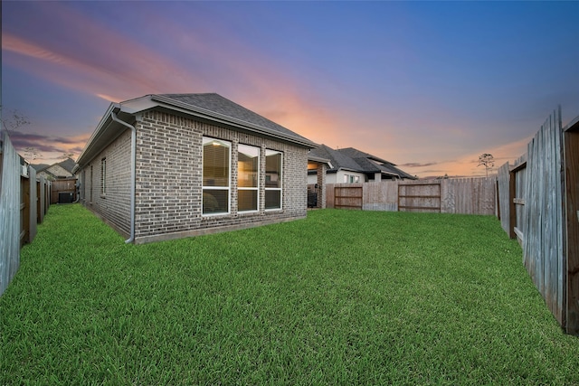 back house at dusk with a lawn