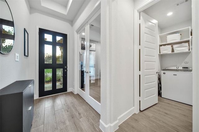 entrance foyer with french doors, light hardwood / wood-style floors, and washer / dryer