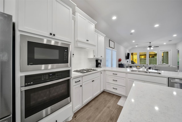 kitchen with light hardwood / wood-style floors, appliances with stainless steel finishes, sink, and white cabinetry