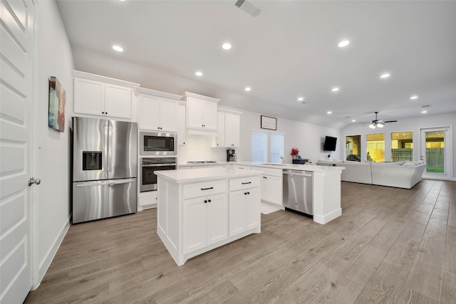 kitchen featuring light wood-type flooring, ceiling fan, white cabinets, appliances with stainless steel finishes, and a center island