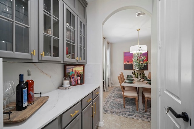 226 Hampton Glen Rd, Montgomery, TX 77356 - interior space with arched walkways, visible vents, decorative backsplash, glass insert cabinets, and gray cabinetry