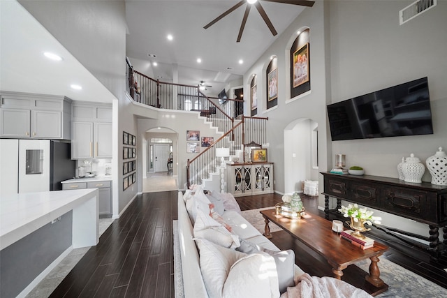 living room with ceiling fan and a towering ceiling