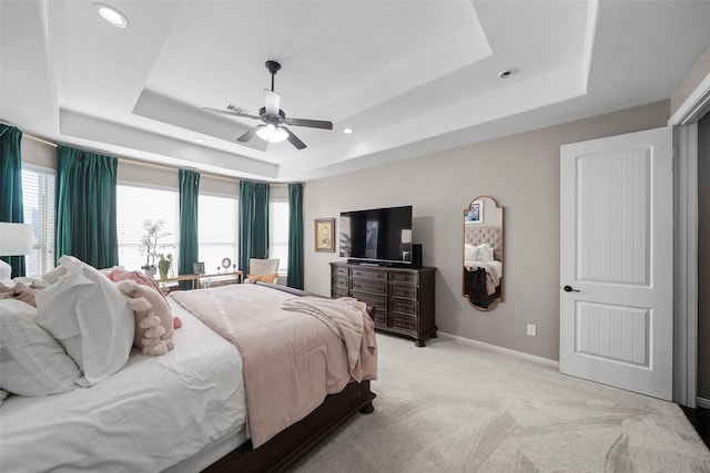 carpeted bedroom with a raised ceiling and ceiling fan