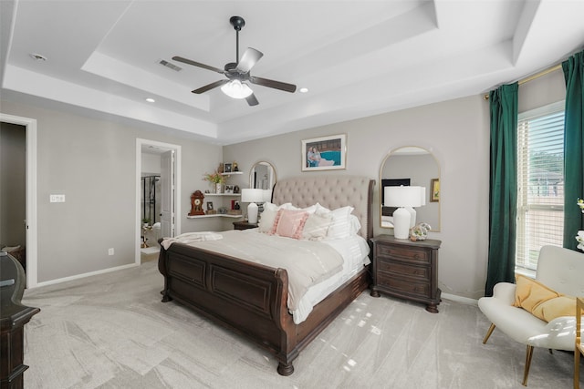 carpeted bedroom featuring a raised ceiling, connected bathroom, and ceiling fan