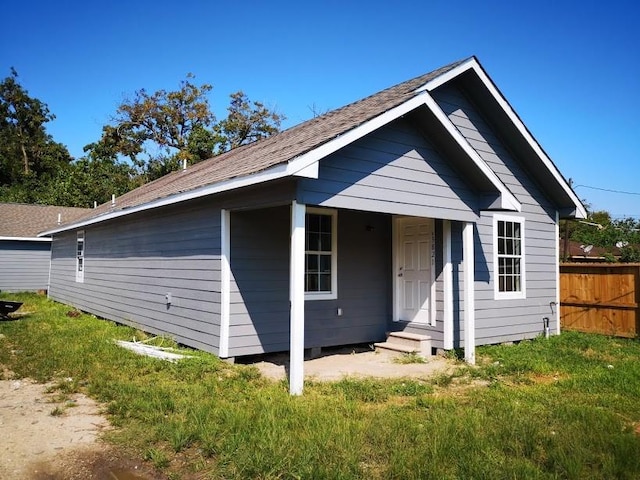 view of front of house with fence, roof with shingles, and a front lawn