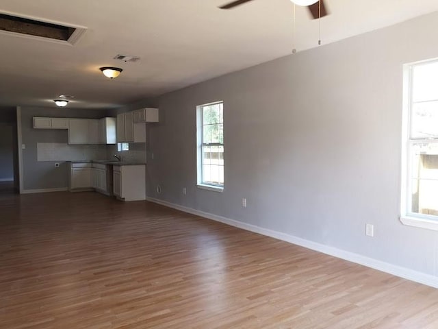 unfurnished living room with ceiling fan, visible vents, baseboards, and light wood-type flooring