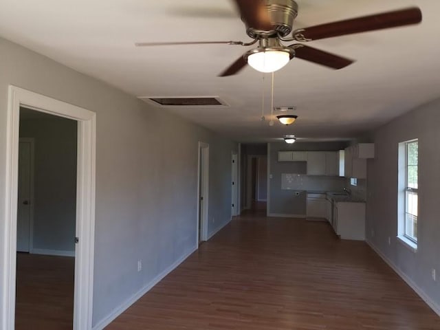 interior space with baseboards, ceiling fan, wood finished floors, and visible vents