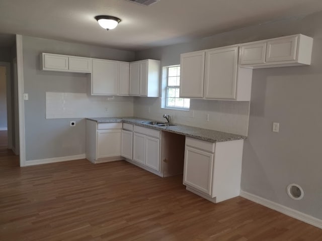 kitchen featuring light stone countertops, wood-type flooring, sink, and white cabinets