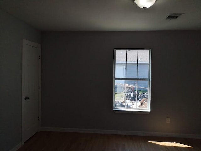 empty room with visible vents, baseboards, and wood finished floors